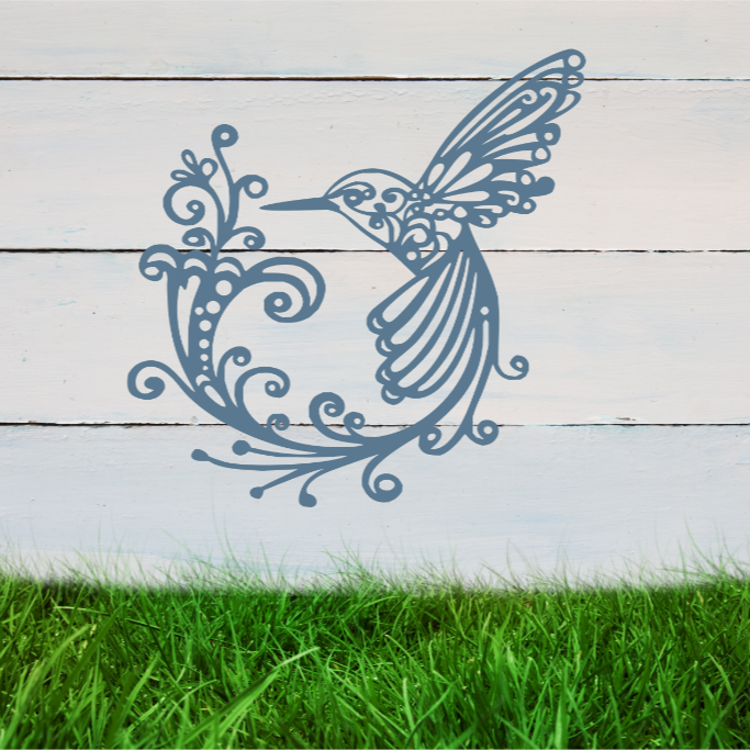 Delicate metal wall art featuring a hummingbird with intricately detailed wings and tail, surrounded by swirling vine patterns, finished in Wedgwood Satin powder coating, mounted on a rustic white wooden backdrop, perfect for adding a touch of nature to an outdoor space