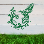 Delicate metal wall art featuring a hummingbird with intricately detailed wings and tail, surrounded by swirling vine patterns, finished in Mistletoe powder coating, mounted on a rustic white wooden backdrop, perfect for adding a touch of nature to an outdoor space.