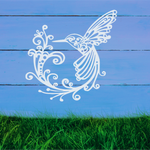 Delicate metal wall art featuring a hummingbird with intricately detailed wings and tail, surrounded by swirling vine patterns, finished in Bright White Gloss powder coating, mounted on a rustic white wooden backdrop, perfect for adding a touch of nature to an outdoor space.