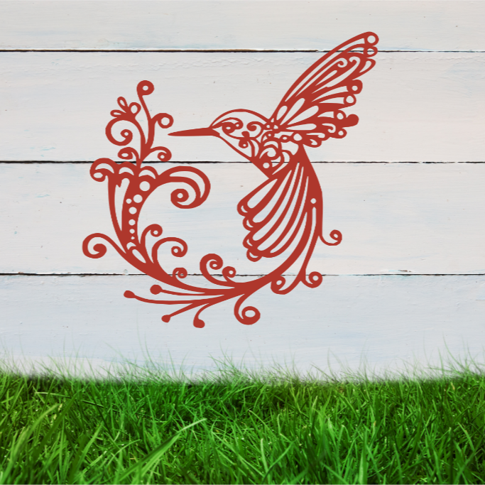Delicate metal wall art featuring a hummingbird with intricately detailed wings and tail, surrounded by swirling vine patterns, finished in Signal Red powder coating, mounted on a rustic white wooden backdrop, perfect for adding a touch of nature to an outdoor space.