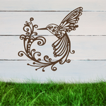 Delicate metal wall art featuring a hummingbird with intricately detailed wings and tail, surrounded by swirling vine patterns, finished in Rust Patina powder coating, mounted on a rustic white wooden backdrop, perfect for adding a touch of nature to an outdoor space.